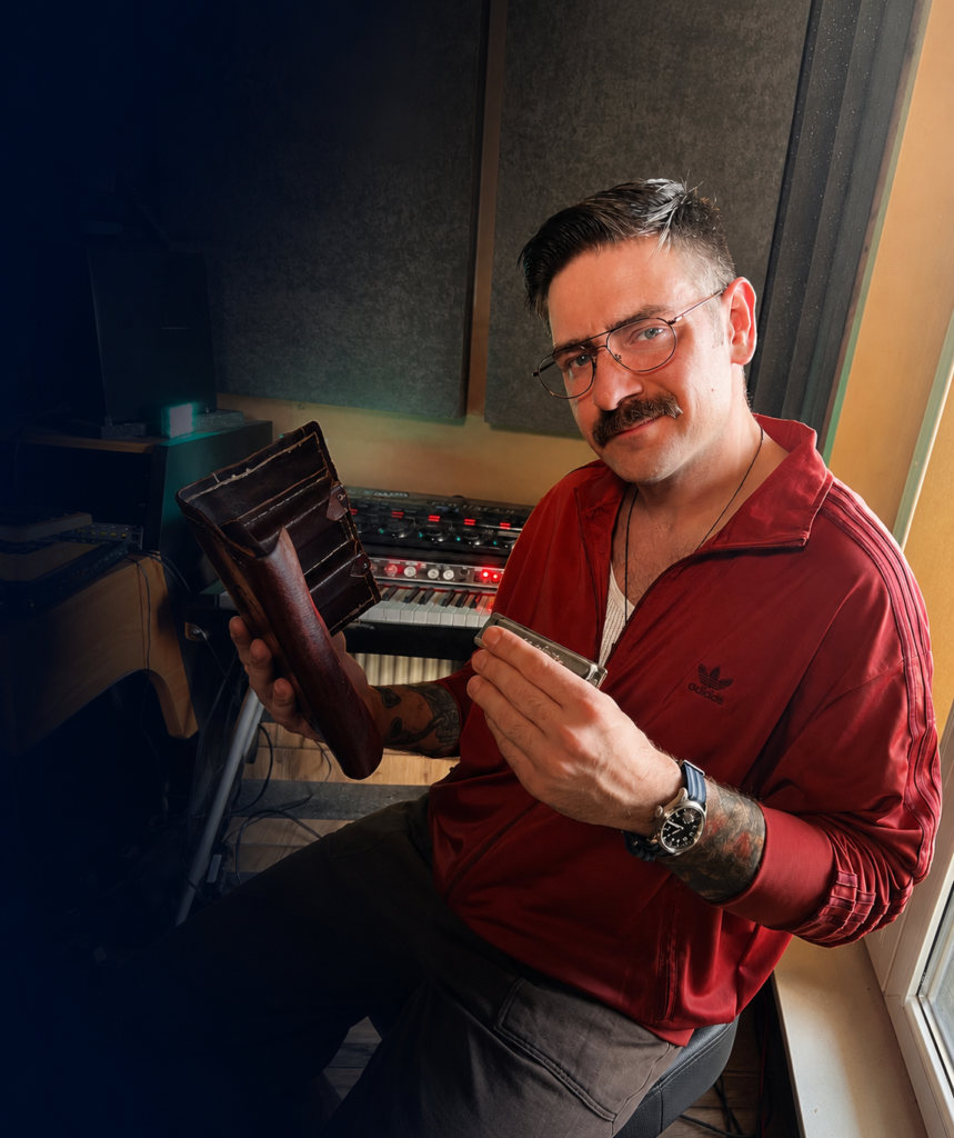 Mieszko Służewski z harmonijką i futerałem na harmonijki w pracowni muzycznej